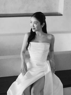 Elegant bride in strapless white gown poses in black and white portrait with serene expression.