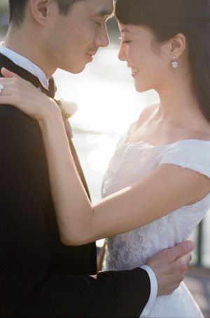 Bride and groom in golden backlight share intimate moment in wedding portrait.