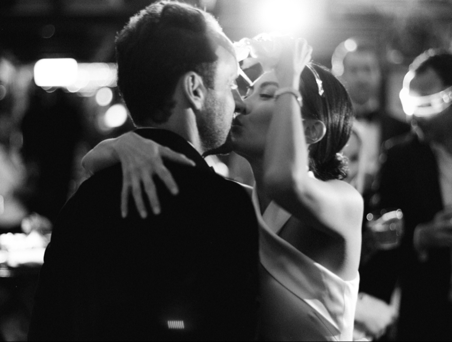 Bride and groom share romantic first dance in black and white wedding photo.