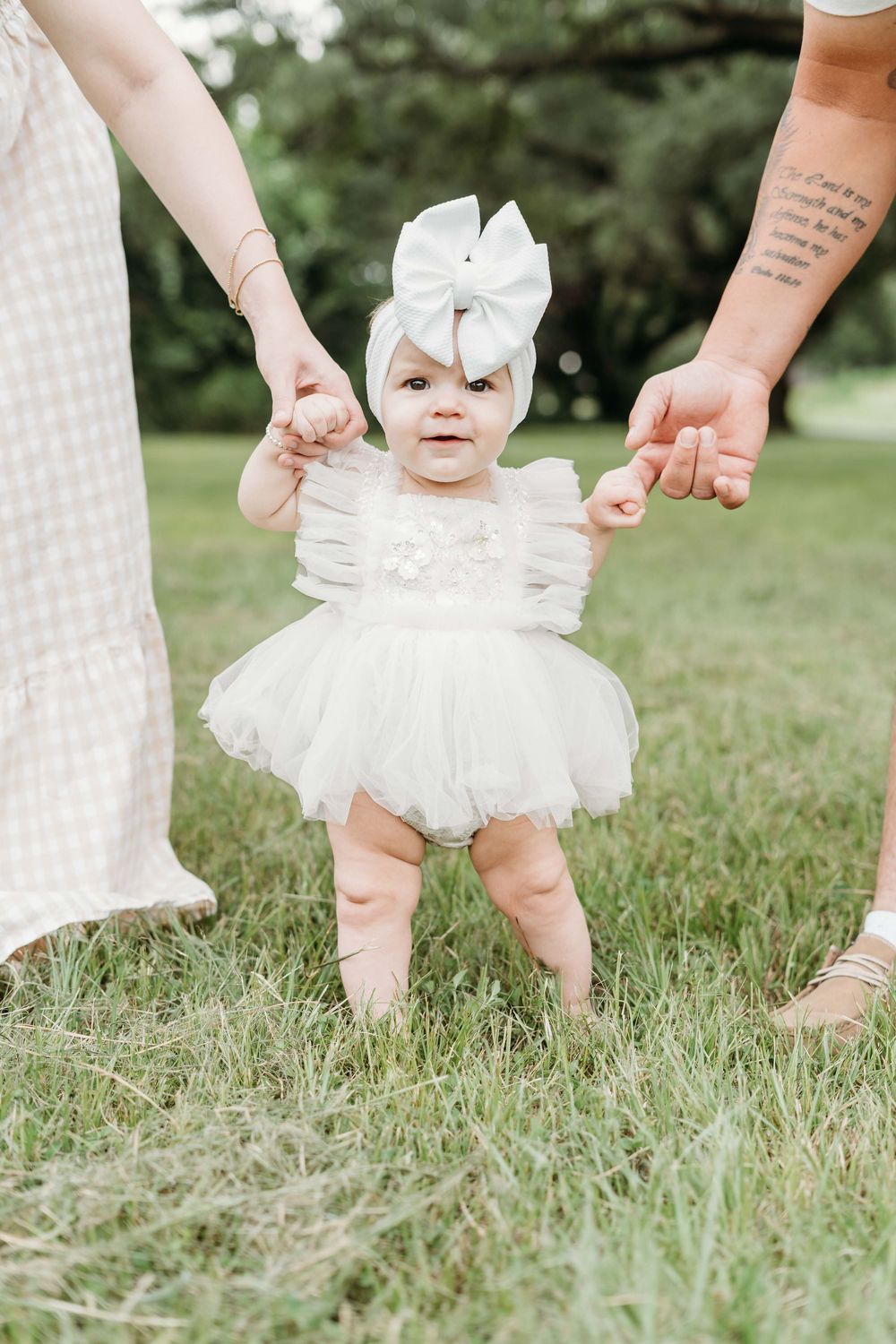 Baby wearing white dress showing steps on grassy lawn while adult hands reach down to support in composite image.