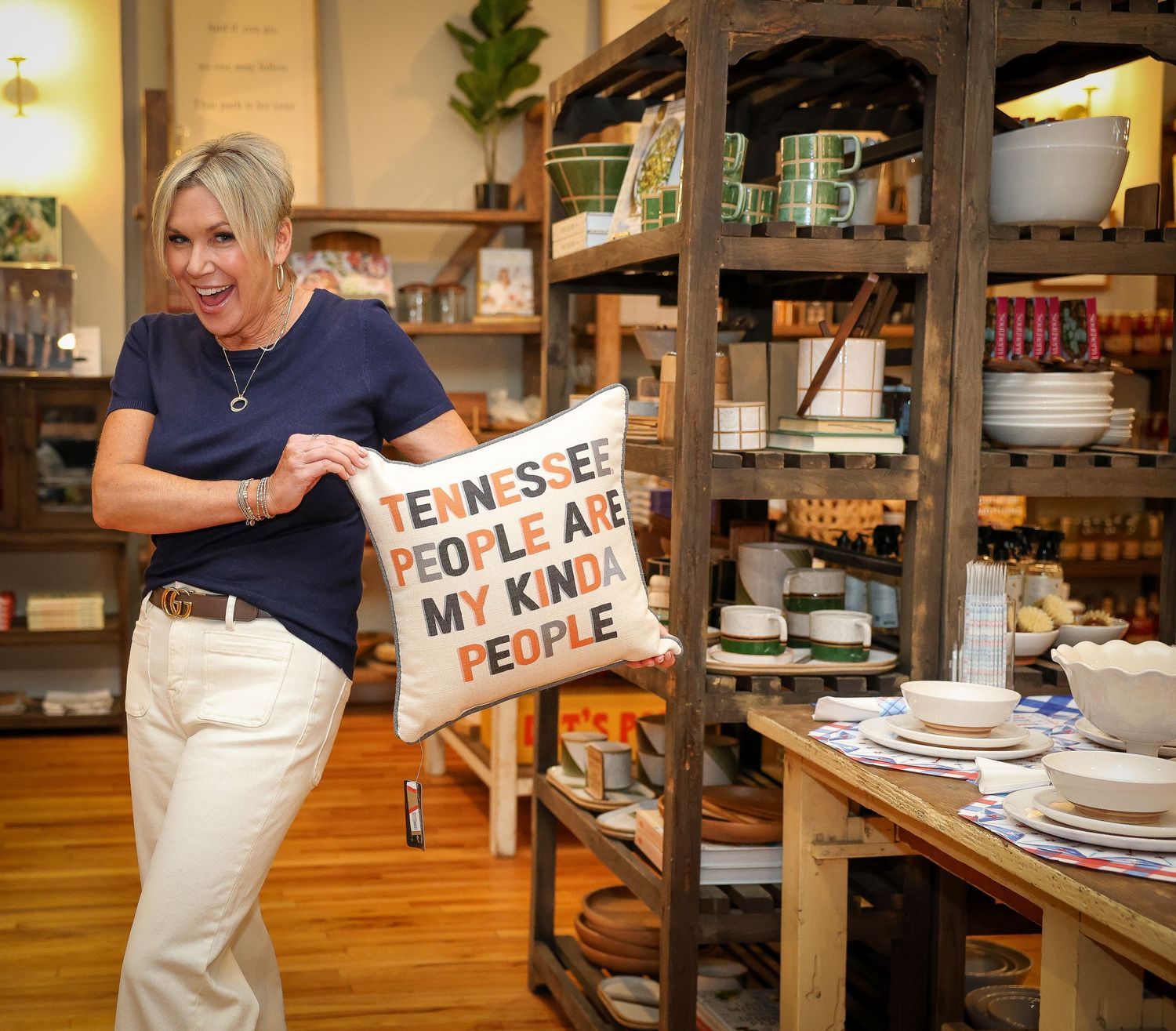 Retail worker arranges display signs in wooden shelving unit at store.