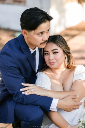 A couple embraces in formal attire for a romantic wedding portrait outdoors in natural lighting.