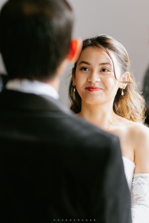 A bride in a white strapless gown gazes lovingly at her groom during their wedding ceremony.