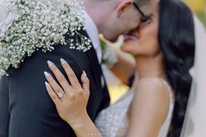 Close-up of a couple's ring-adorned hand during an intimate wedding moment with baby's breath flowers.