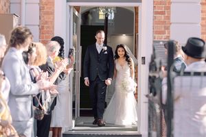 Guests shower rose petals on a couple exiting a brick church building after their wedding celebration.