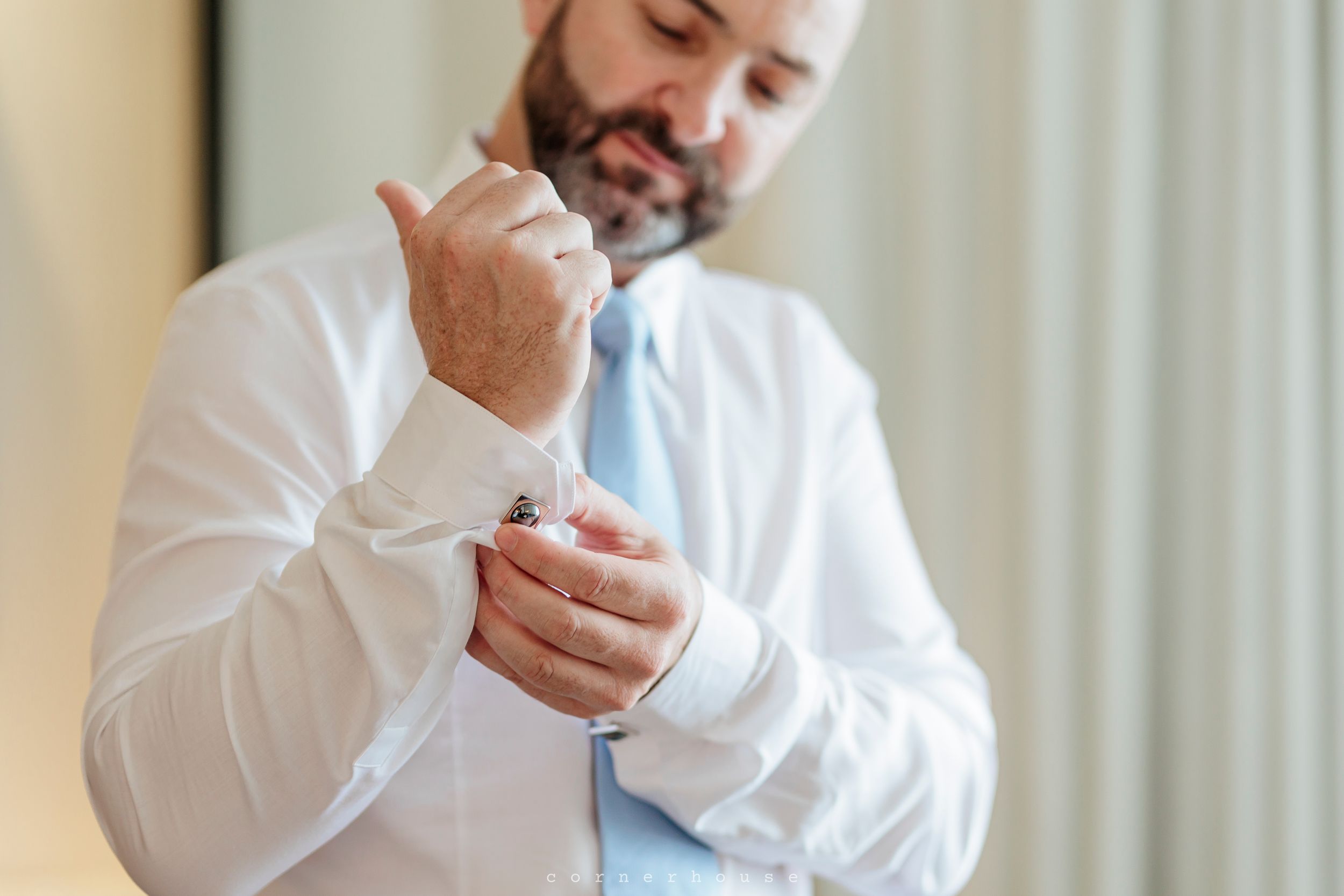 A person wearing a white shirt scrolls on their smartphone while sitting in an office or room.