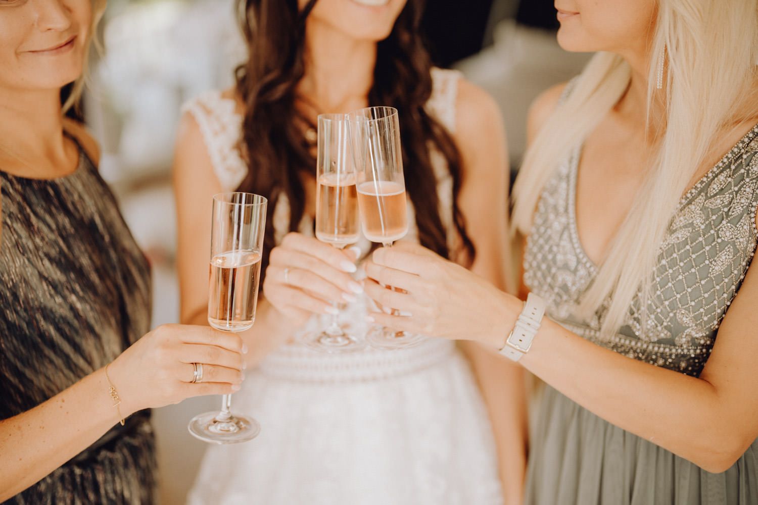 Women in elegant dresses toast with champagne glasses at formal celebration.