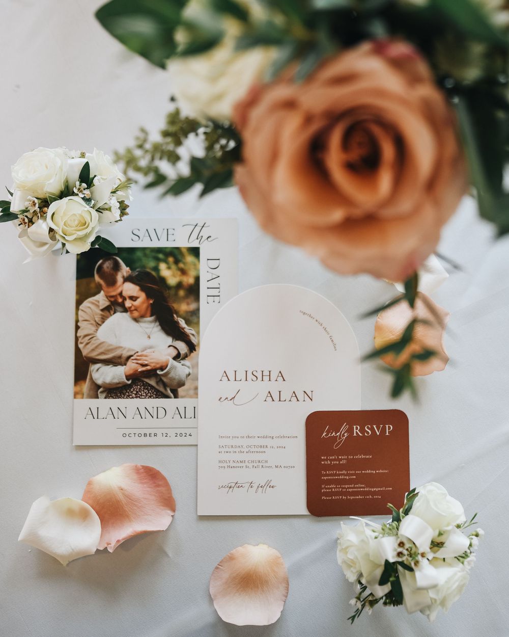 Wedding stationery suite with save the date, invitation, and RSVP card surrounded by roses.