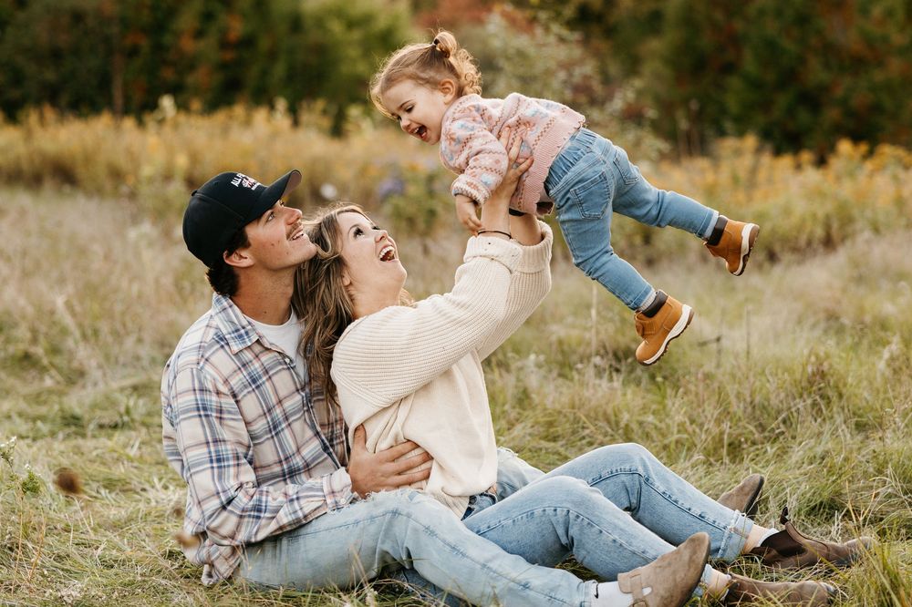 A playful moment captured in a grassy field during a casual outdoor photo session.
