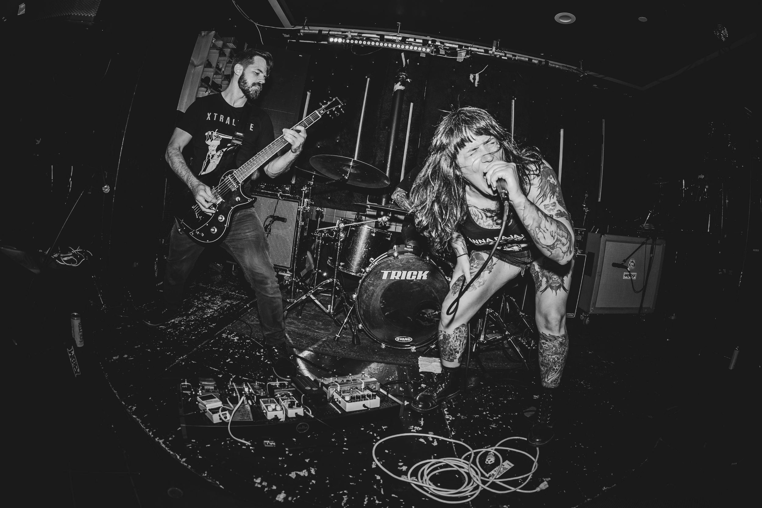 Black and white photo of guitarist and vocalist performing energetically on a small stage.