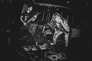 Black and white photo of guitarist and vocalist performing energetically on a small stage.