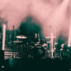 Drummer performing on foggy stage with Ludwig drum kit under pink and purple stage lights.