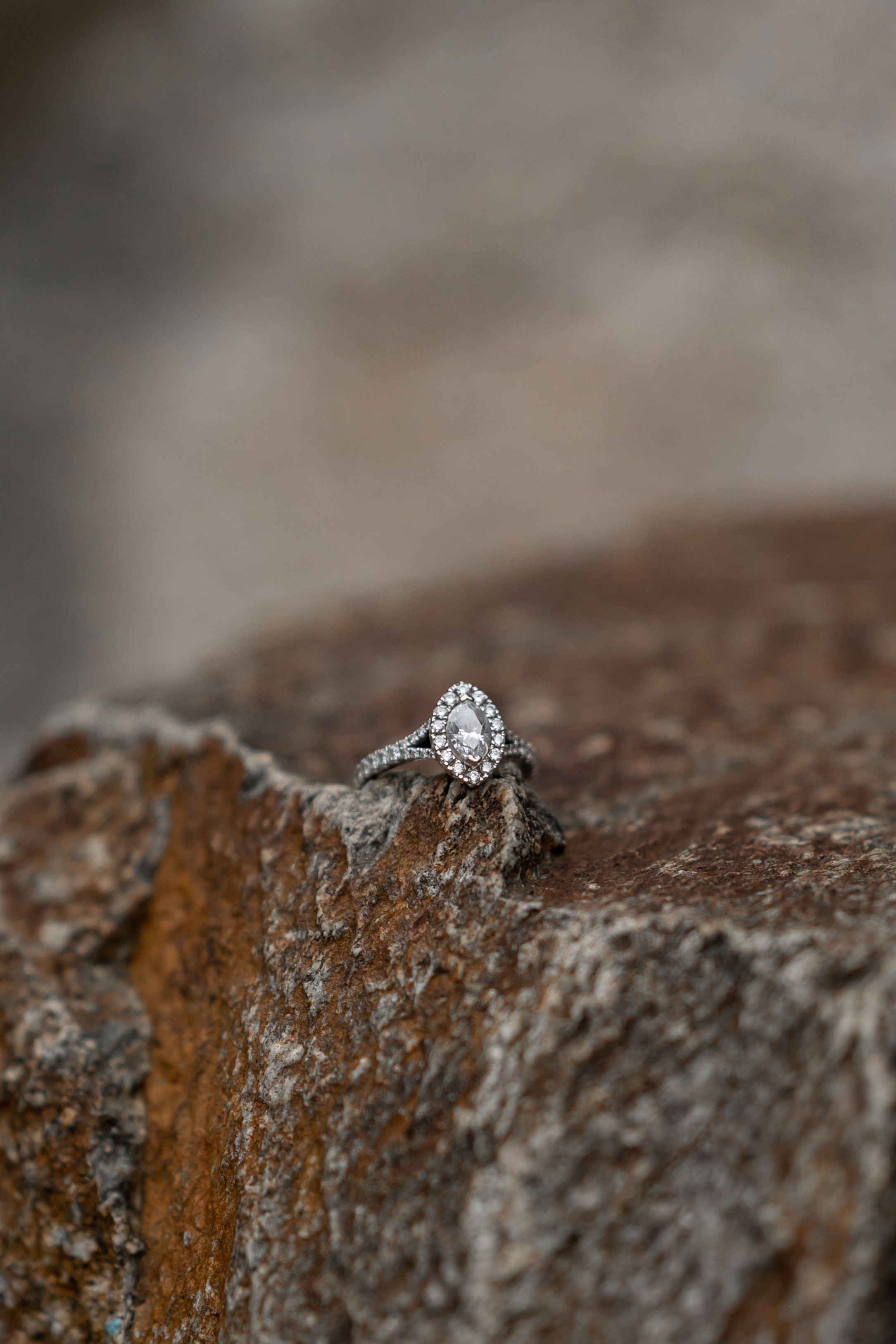 A stunning diamond engagement ring photographed on textured stone surface.