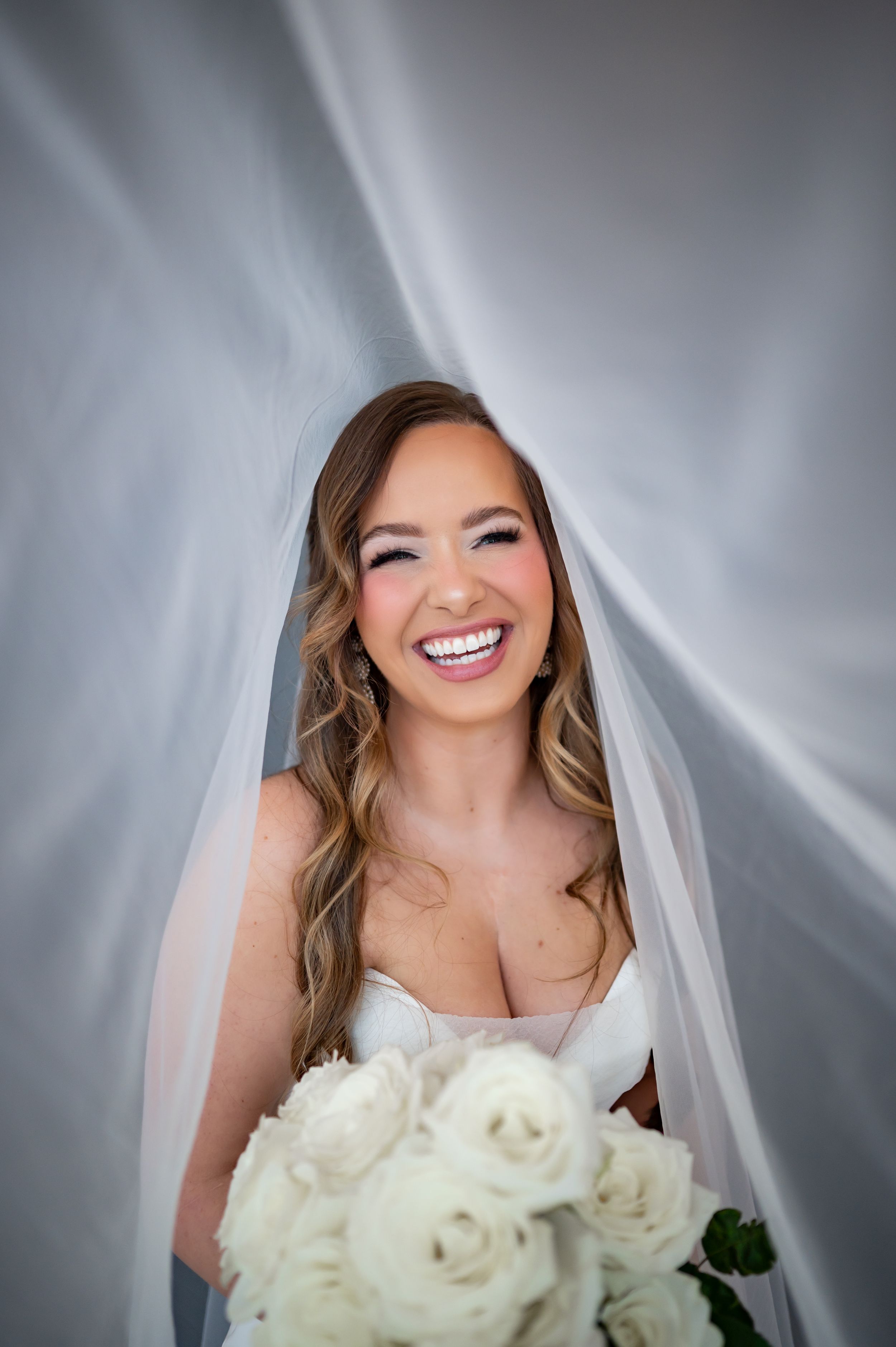 A bridal portrait sequence showing different expressions and angles while holding a white rose bouquet against a gray background.