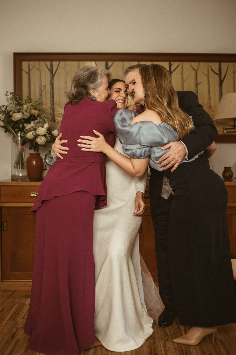 Emotional wedding moment captured as three women share a warm group embrace.