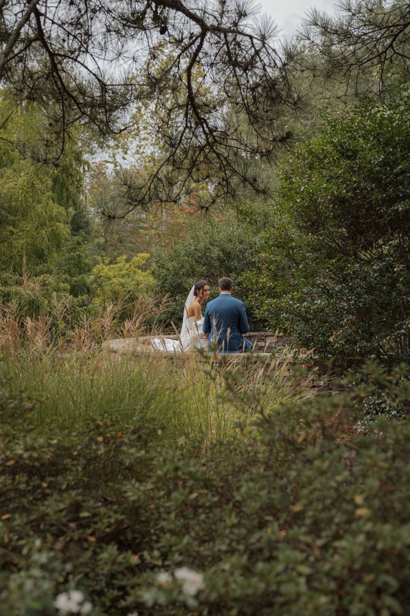 Distant view of couple walking through natural garden landscape.