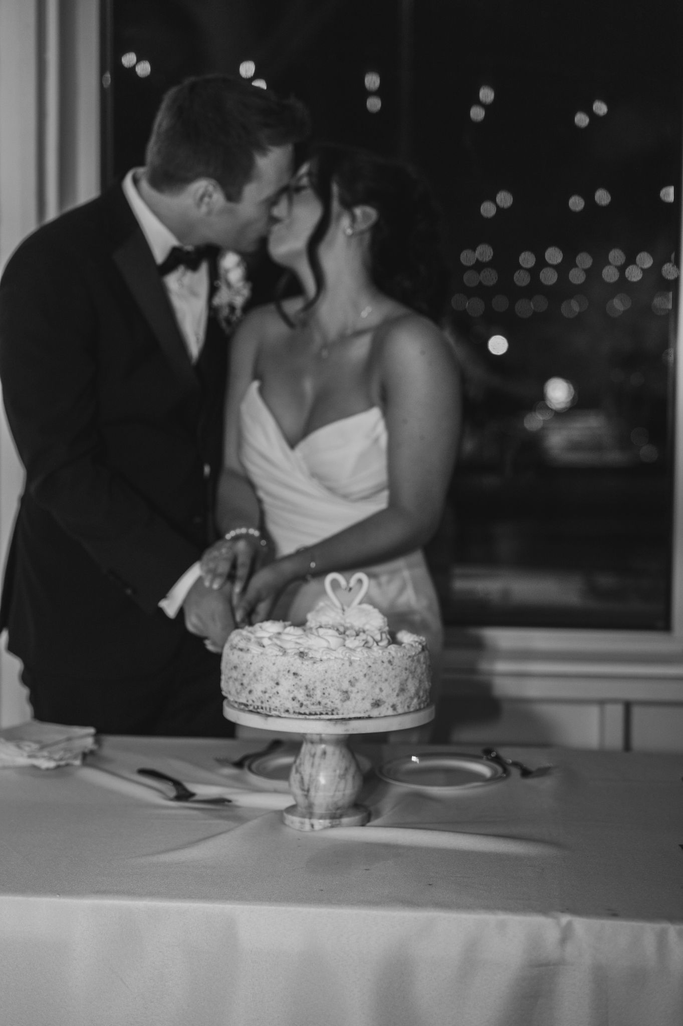 Intimate black and white photos of newlyweds cutting their wedding cake together.