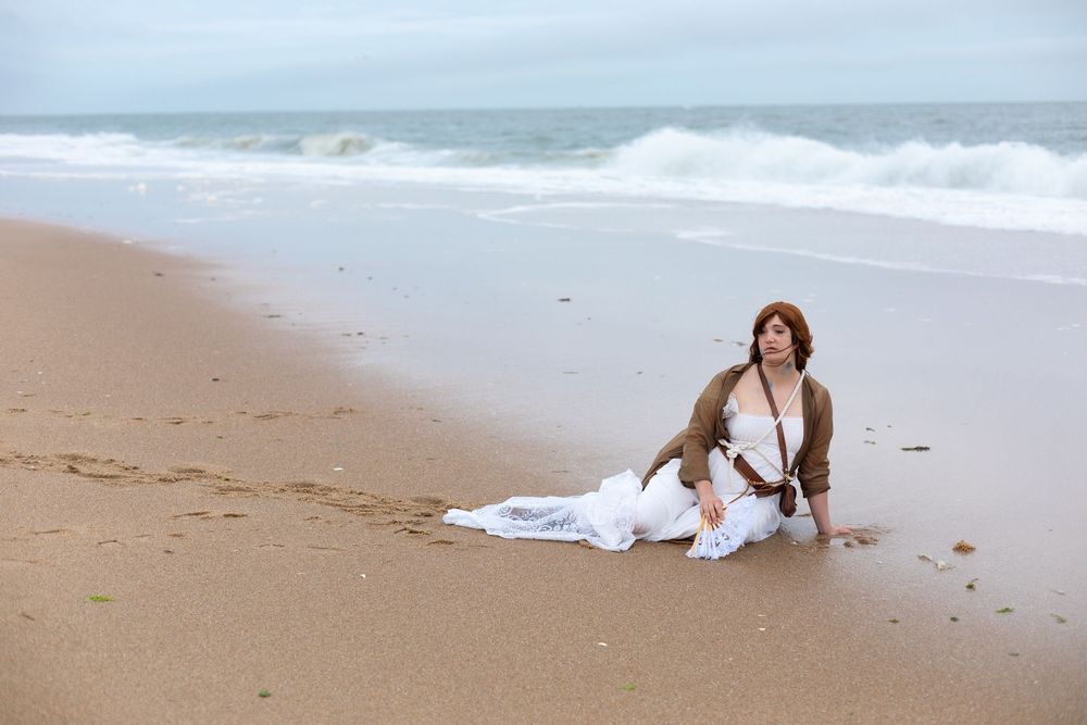 A woman dressed as a pireate sits int he sand forlonly