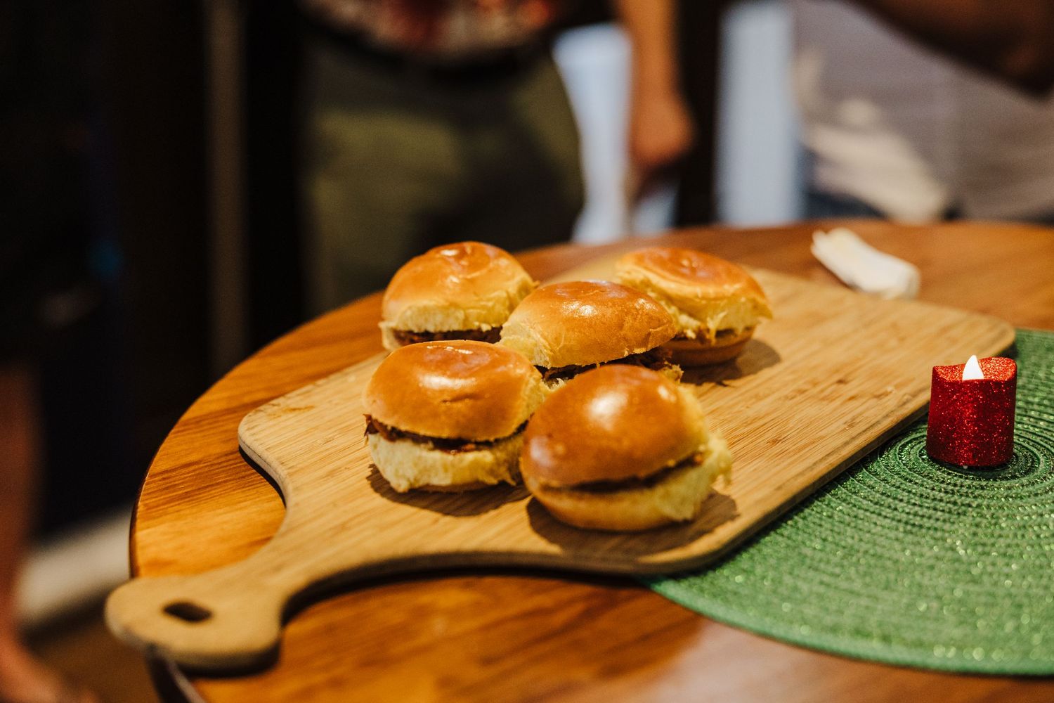 Wooden serving board with fresh slider burgers on display at a restaurant.