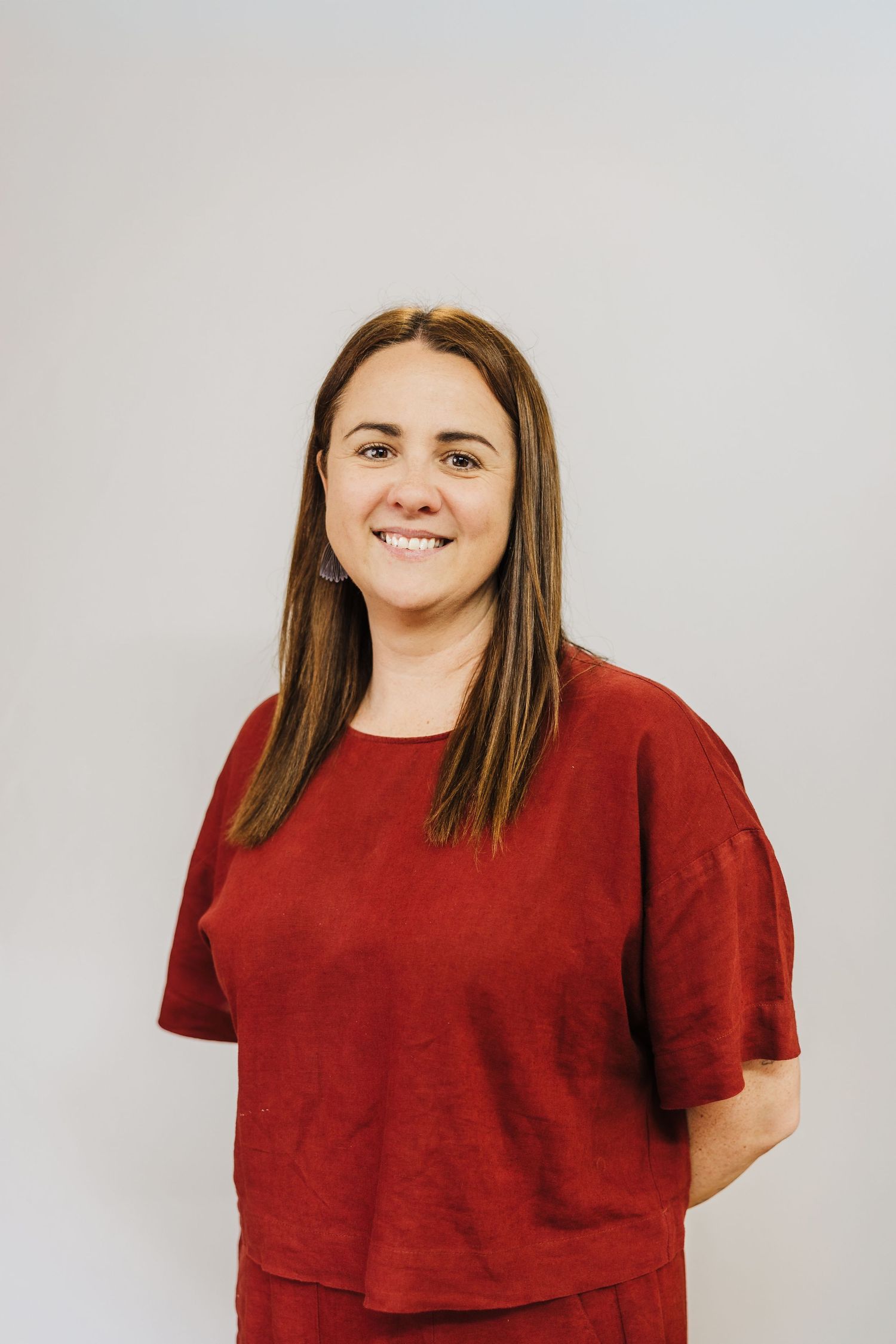 Studio portrait of a person wearing a casual red t-shirt against a light background.