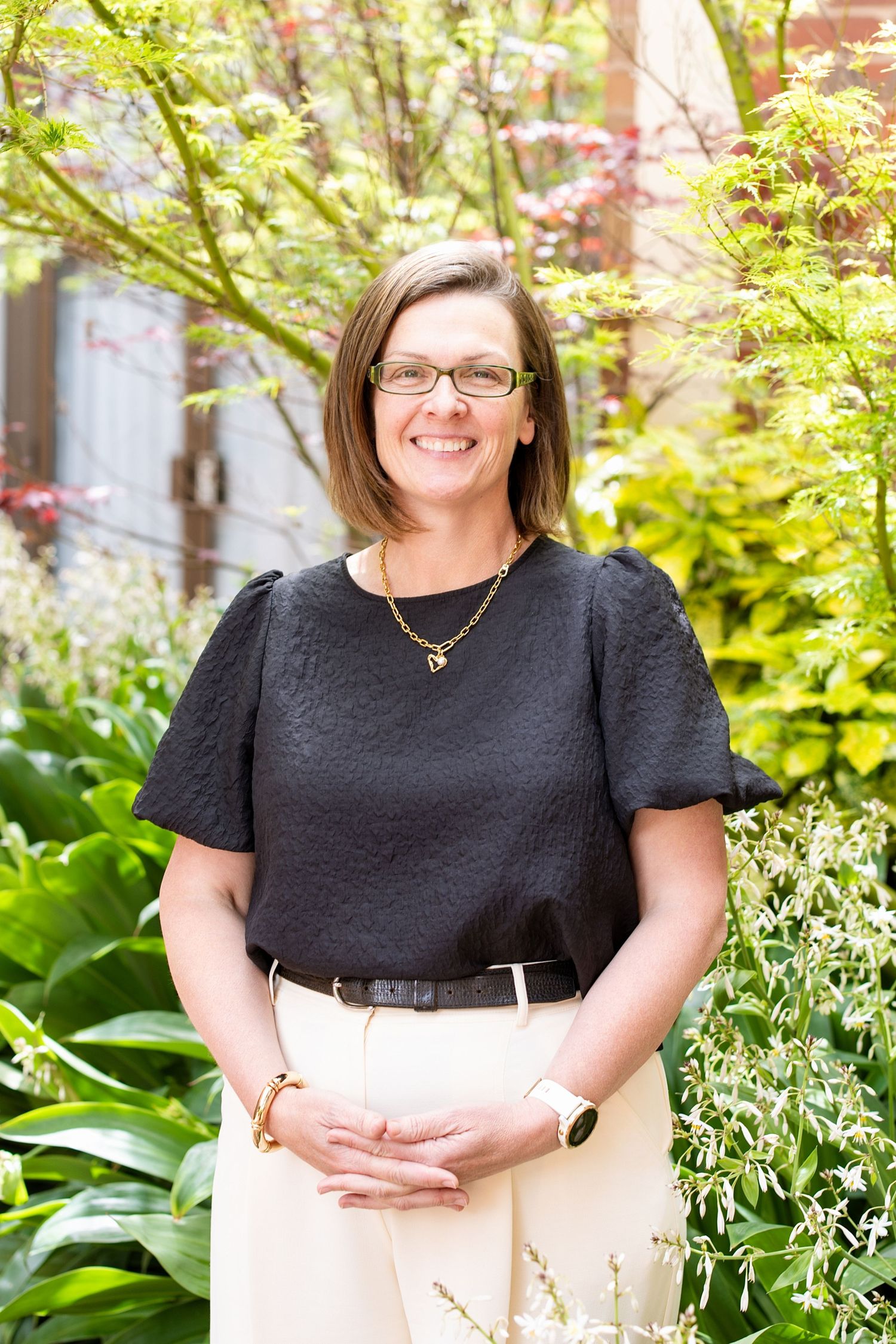 A series of professional outdoor portraits showing someone in a black top against a backdrop of lush green foliage and flowers.