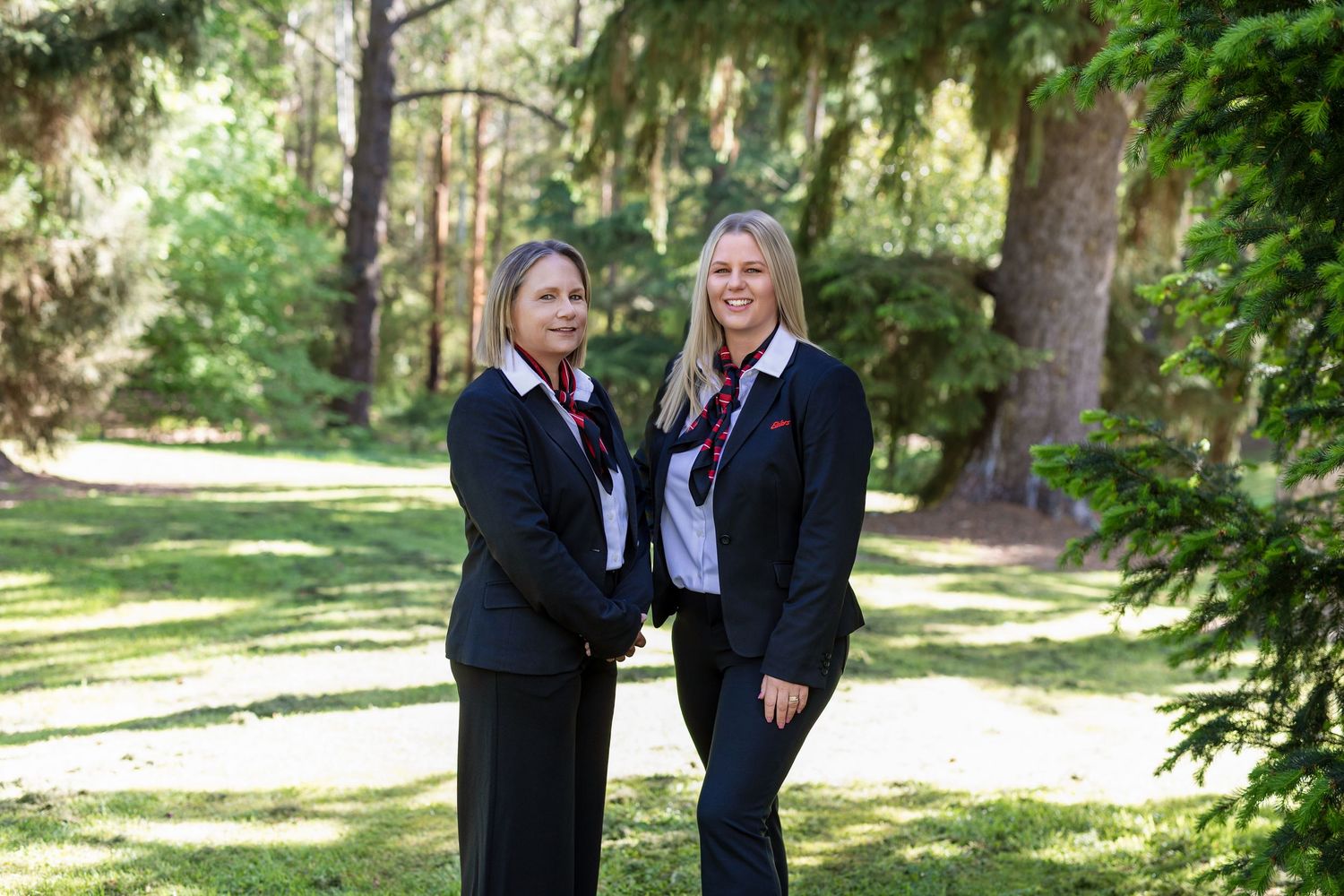 Professional portrait series in a sunlit forest setting with formal business attire and red accents.