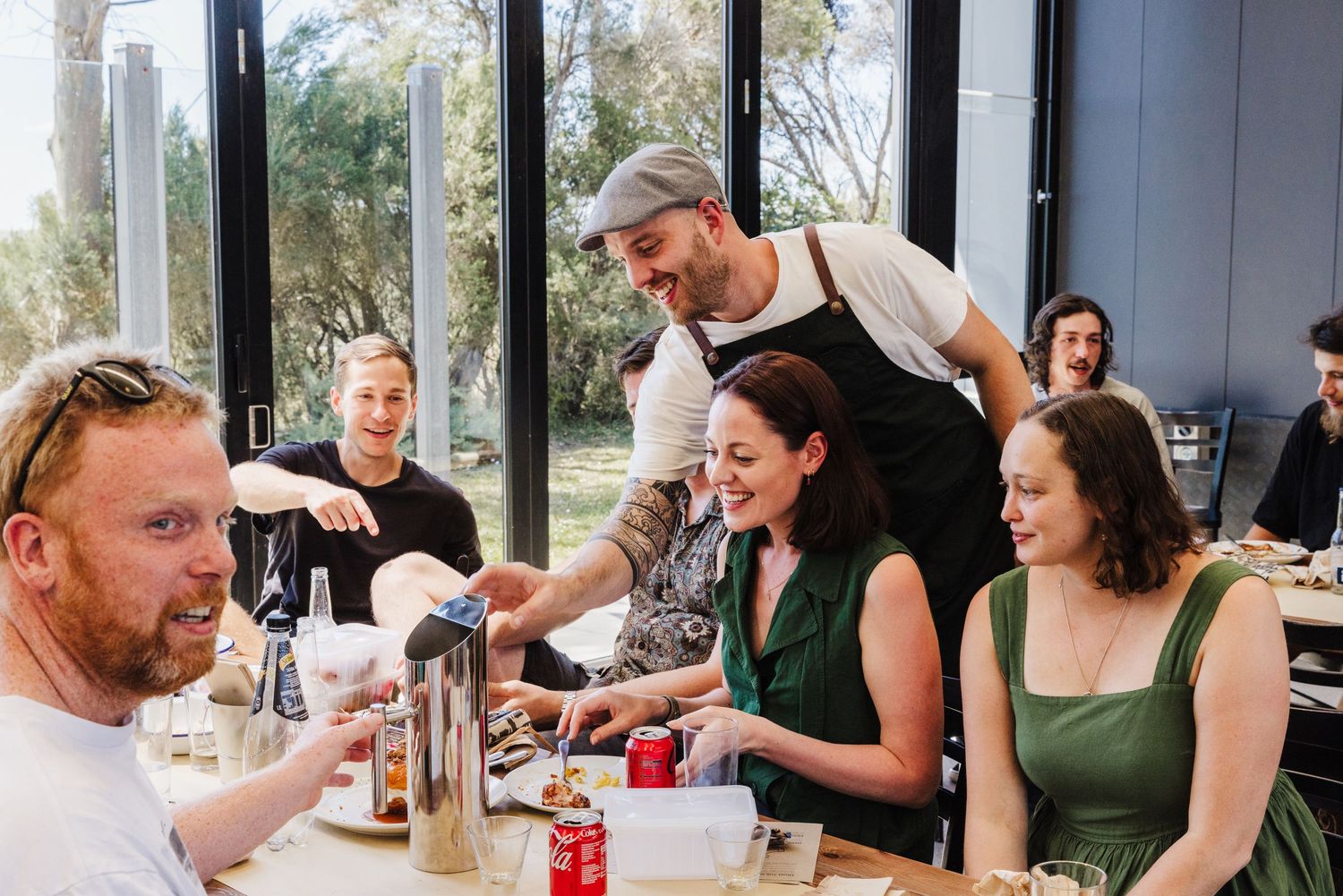 Staff member in apron serving customers at a bright modern restaurant.