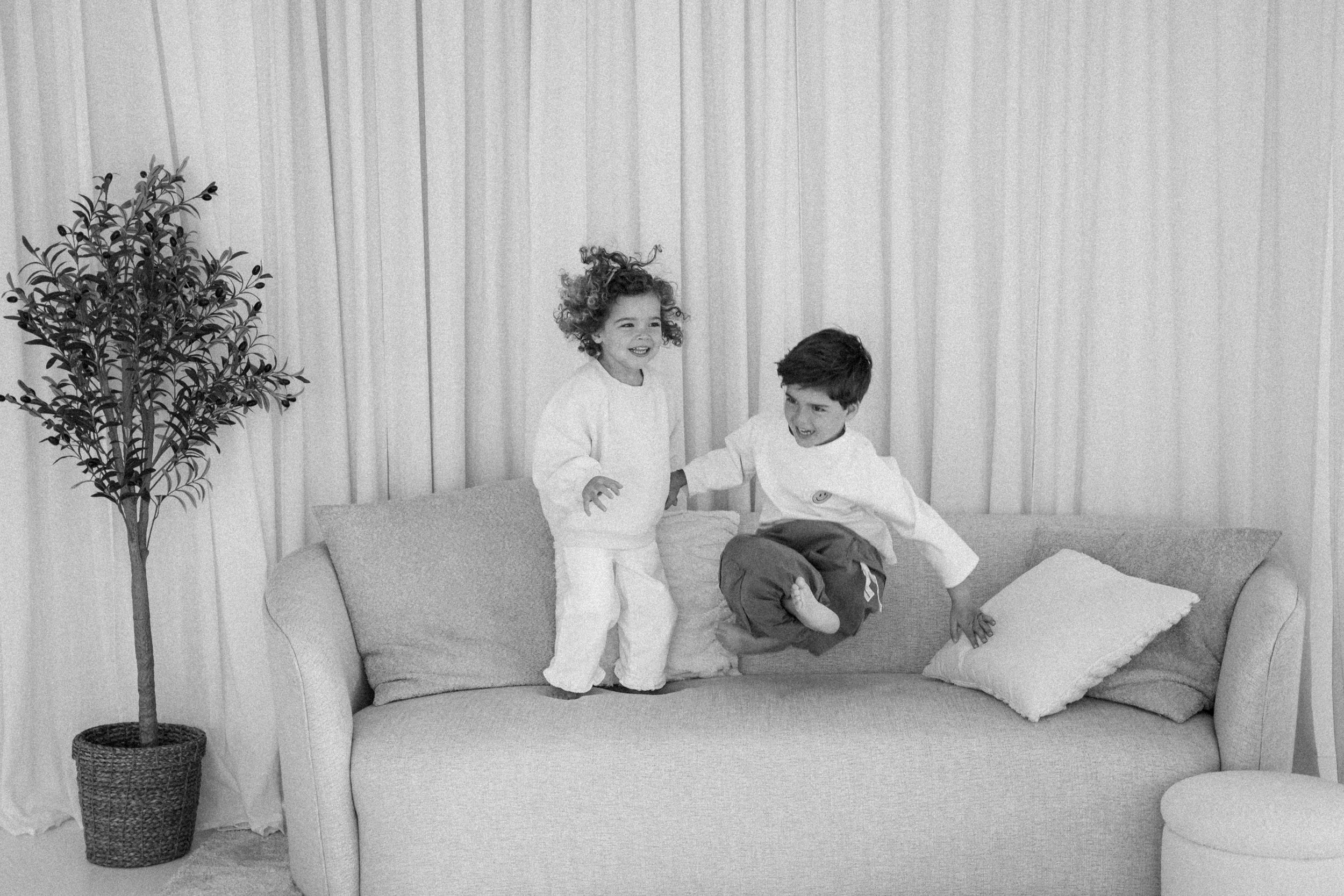 Broer en zus lachen samen tijdens een familieshoot in studio.