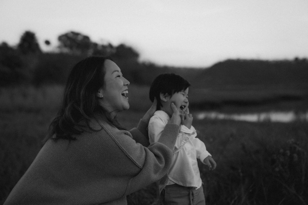 Joyful moment shared between parent and child in a field at dusk.