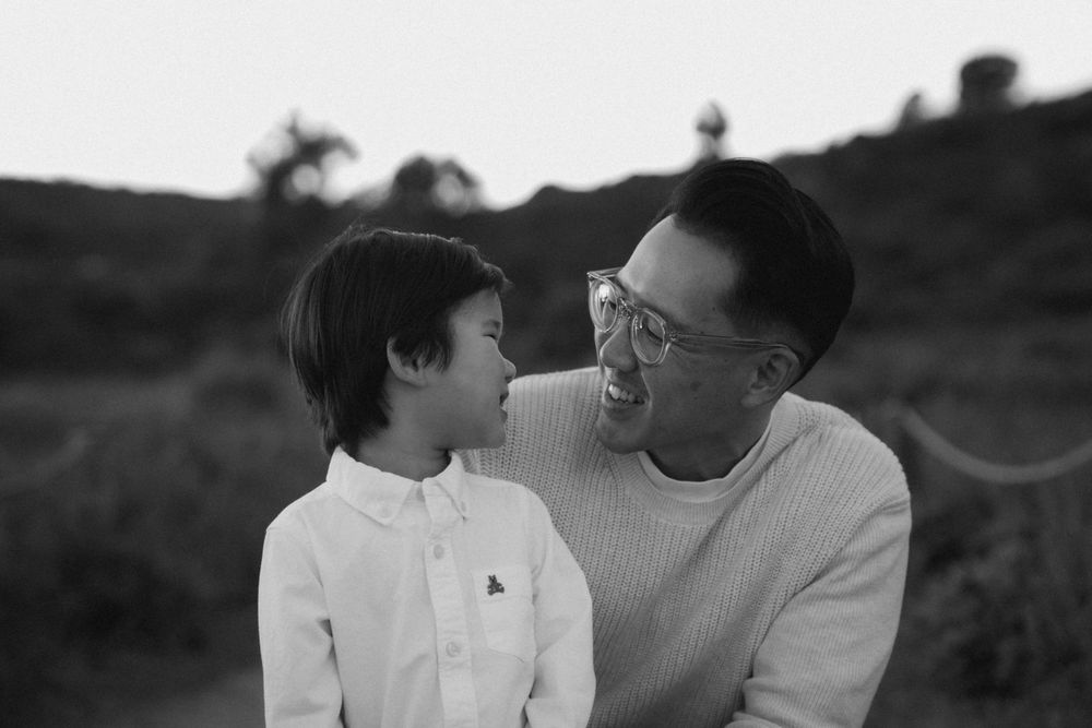 An intimate black and white portrait of a parent and child sharing a tender moment outdoors.