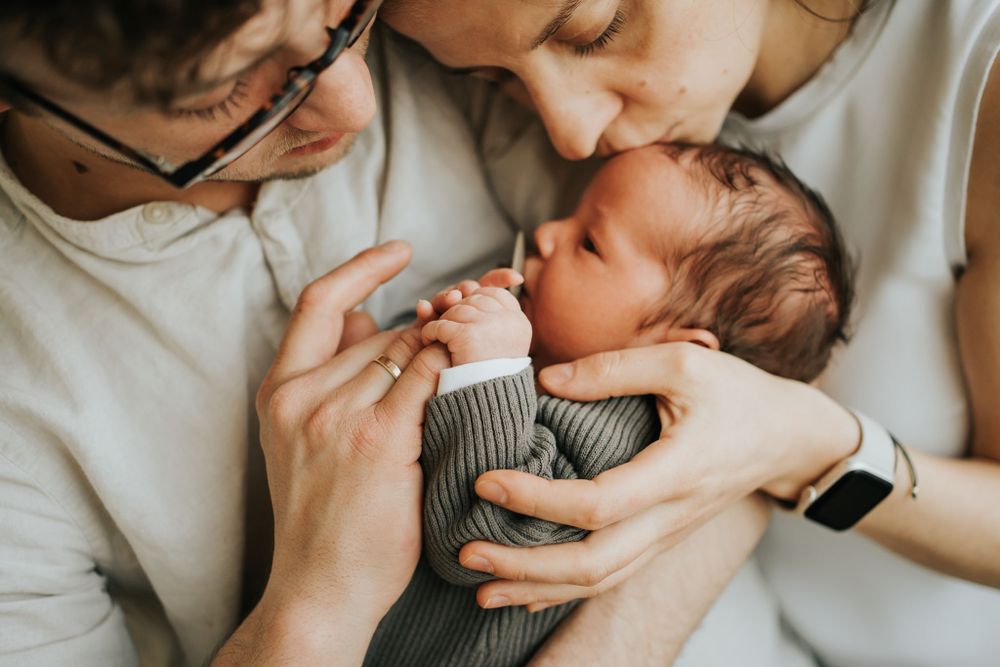 mama i tata trzymają synka, mama go całuje - sesja Kraków