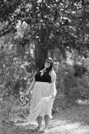 A black and white photo series shows a person in a white dress twirling playfully in a wooded outdoor setting.