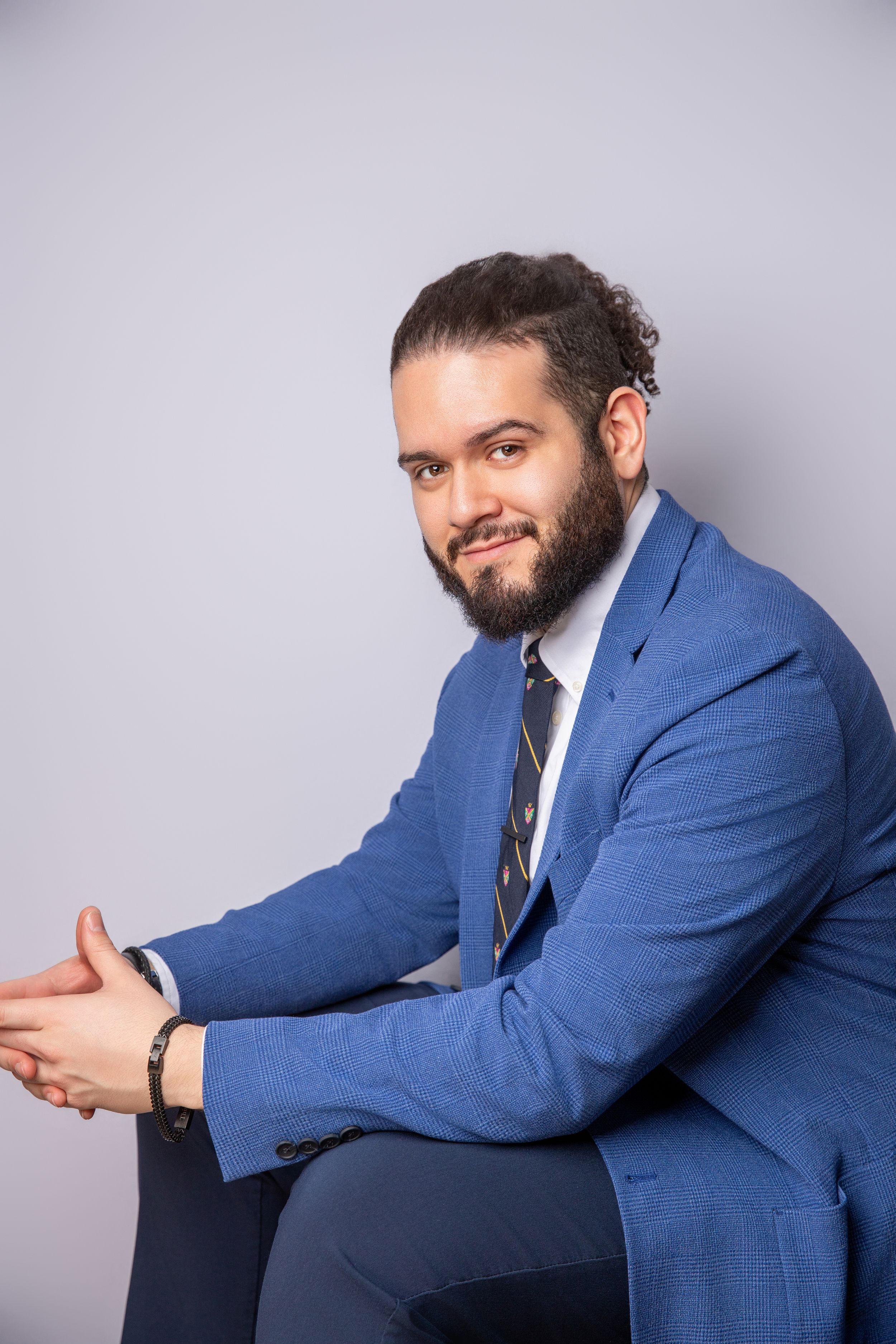 Person in blue blazer smiling while seated against grey backdrop.