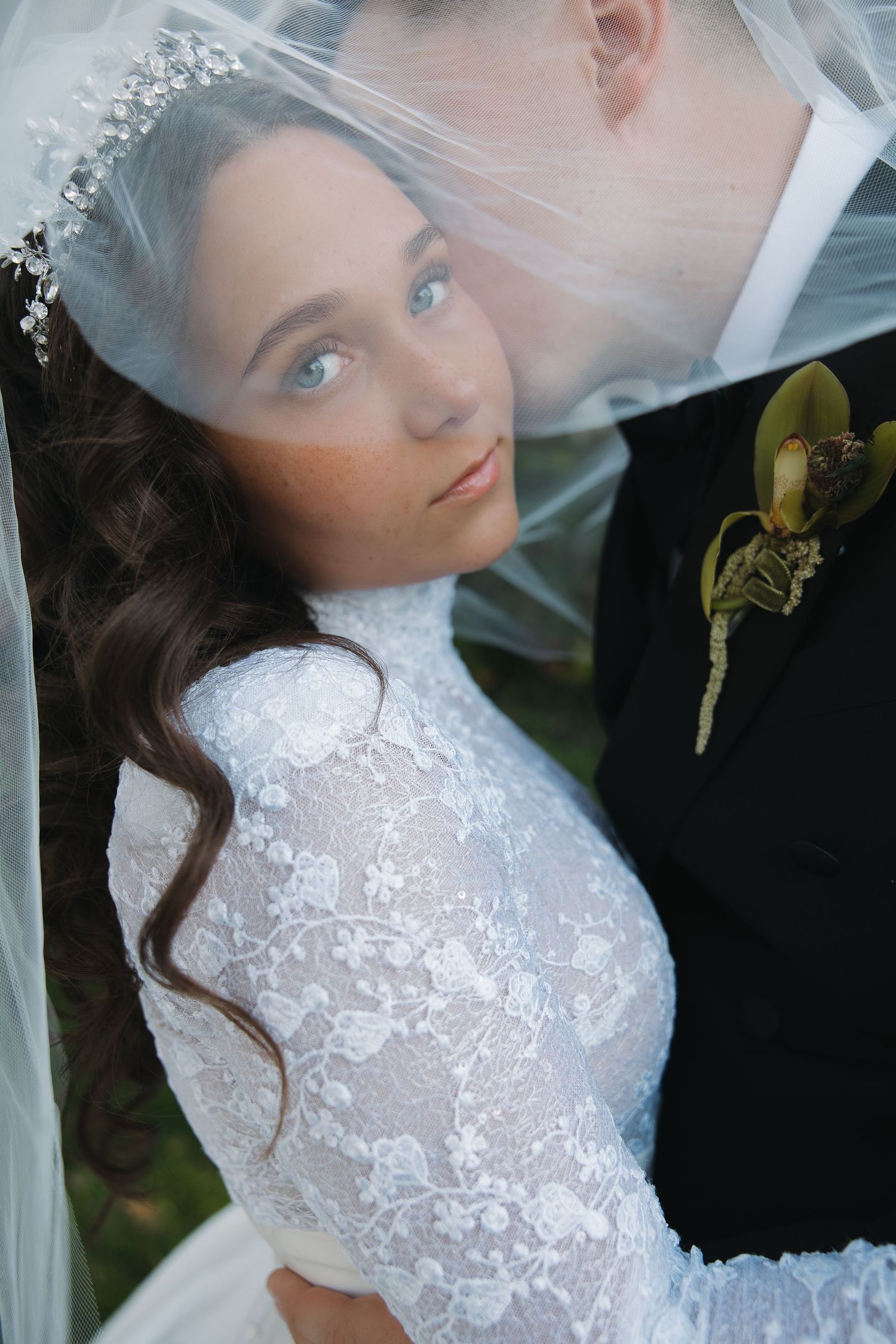 A couple shares a tender kiss under a bright white pergola during their wedding celebration.