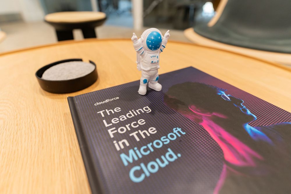Astronaut figurine on a NewForce book titled The Leading Force In The Microsoft Cloud on a wooden table.