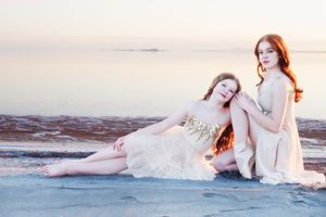 Red head ballerina sisters gracefully along the pink water beach of Great Salt Lake at sunset creating dreamy portraits.