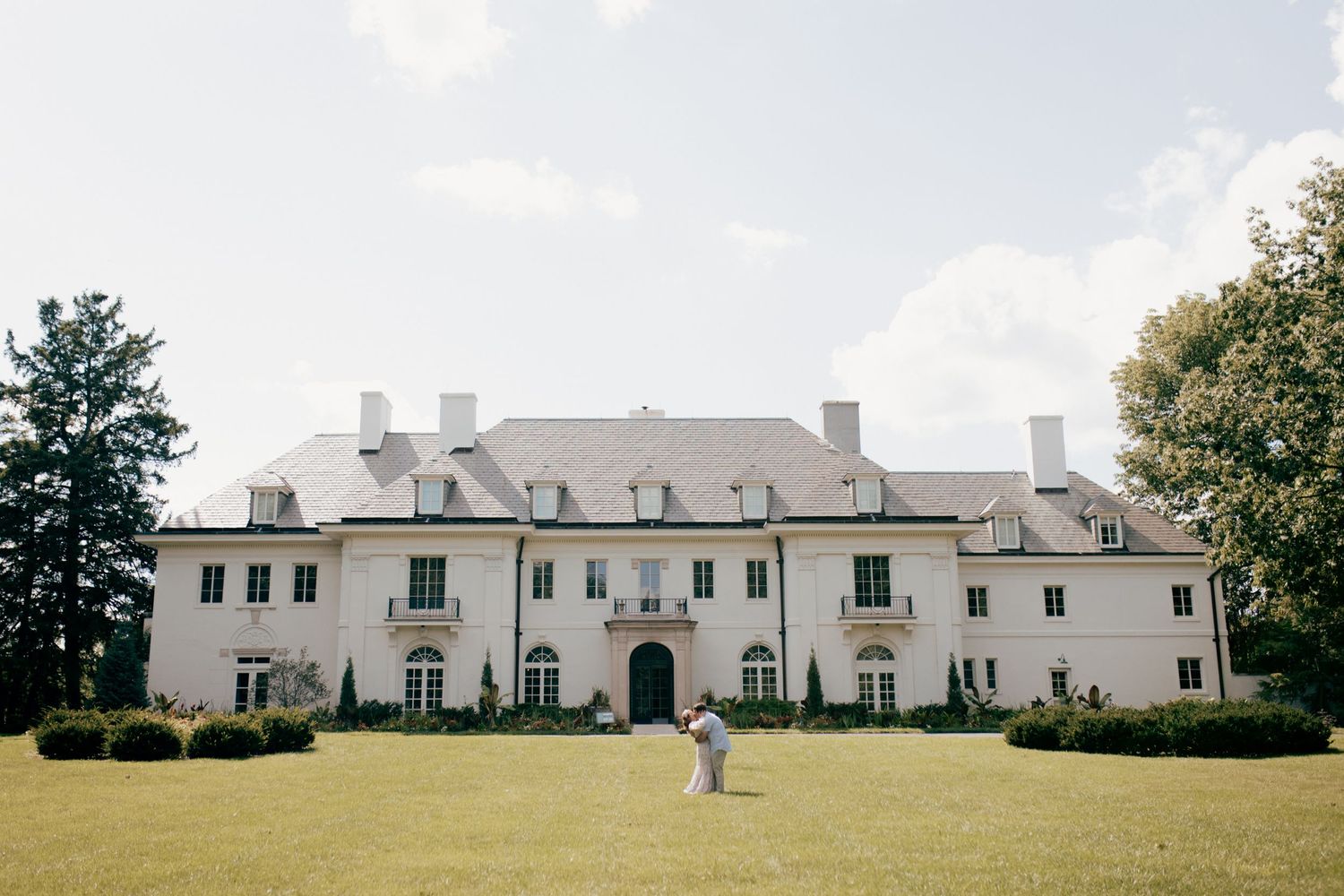 A panoramic view of a large white colonial style building with symmetrical architecture.