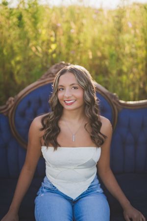 A white top and blue jeans ensemble photographed against a navy blue backdrop in golden sunlight.