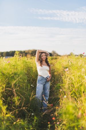 Candid outdoor portrait session in a wildflower field during golden hour with blue jeans and white top.