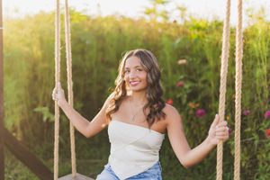 Joyful portrait on a rustic rope swing with natural greenery background.