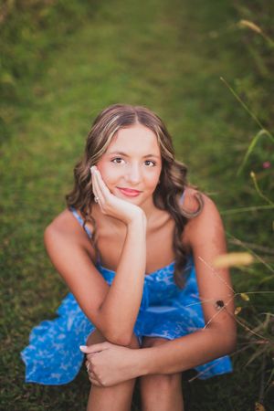 A person wearing a bright blue dress poses in the grass in a creative photo series.