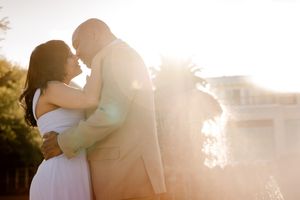 Couple embracing in golden backlit sunset glow, sharing a romantic moment outdoors near a building. Folly Beach/Charleston SC