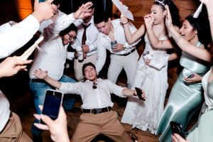Wedding party guests dance energetically on the dance floor during reception celebration.