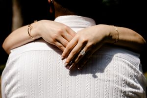 Close-up of a woman's hands with a diamond engagement ring and gold bracelet wrapped around a man's back.
Summerville/Charleston, SC
