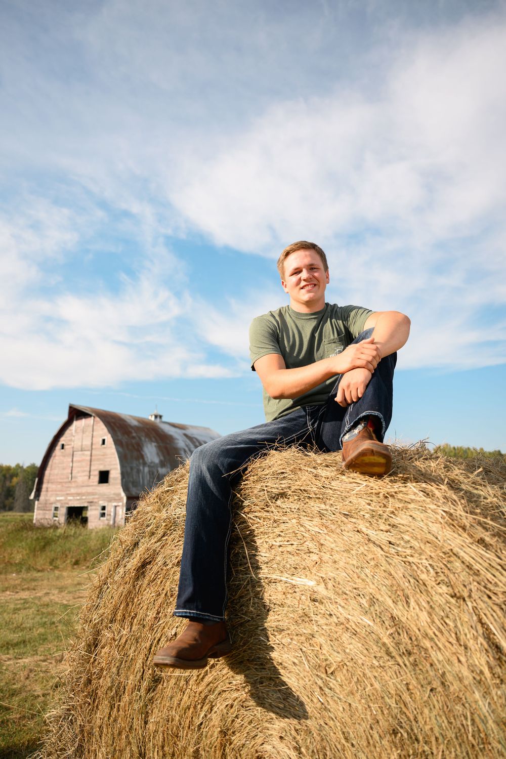 Senior photography featuring Jaxin on hay bale in field
