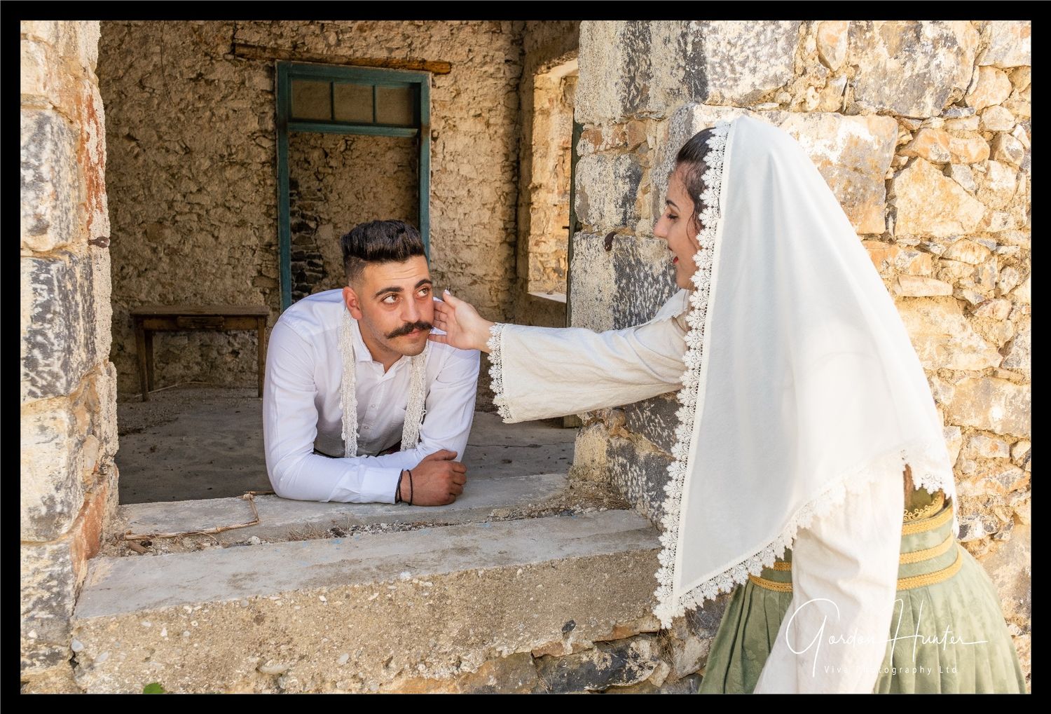 Greek Bride and Groom with Groom leaning through old derelict building.