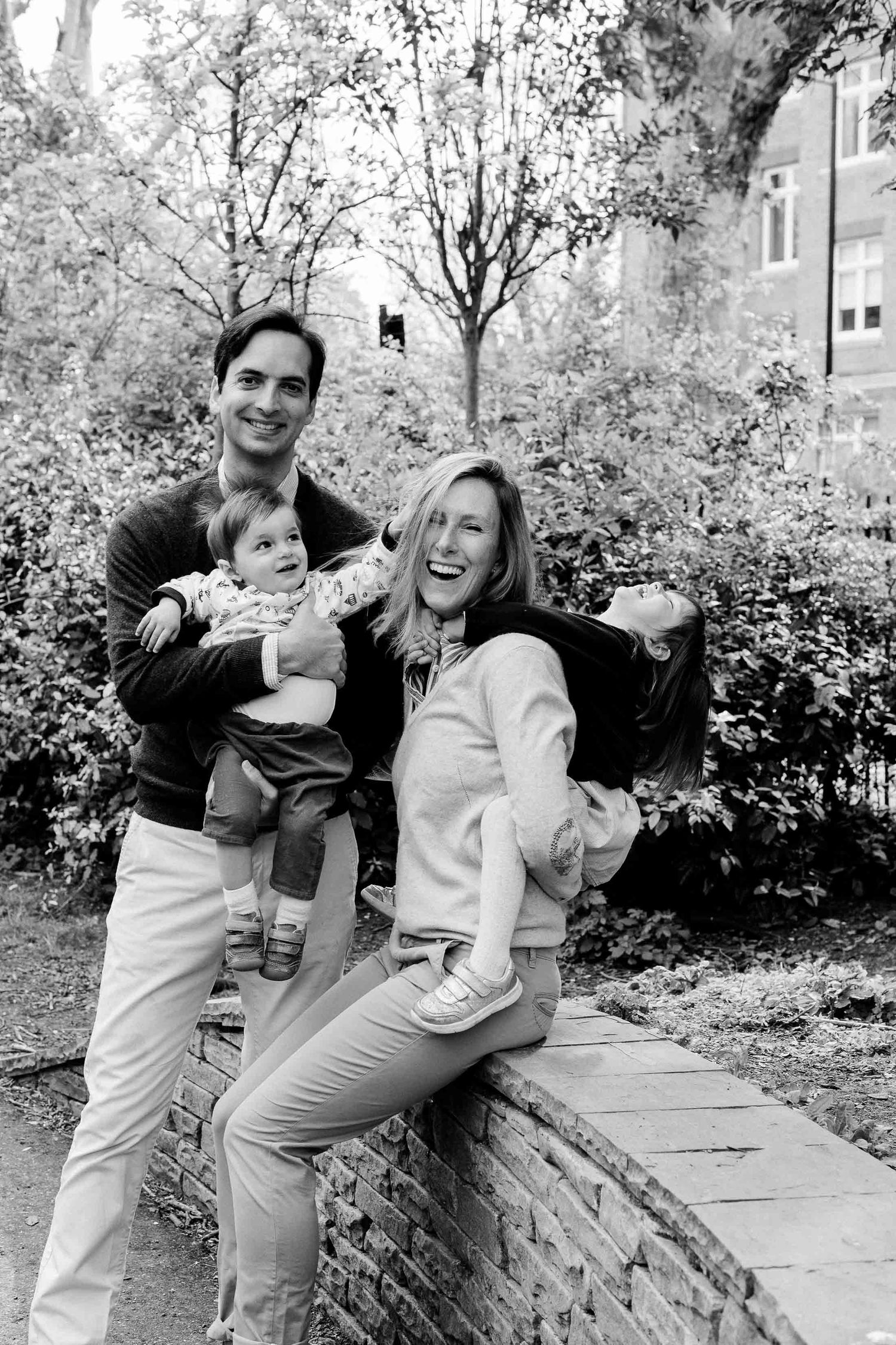 A family in a park enjoying their family photography session in Zurich. Mum is laughing while the kids are pulling at her.
