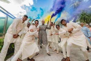 Festive celebration with colorful smoke bombs and coordinated white outfits on a sunny day.
