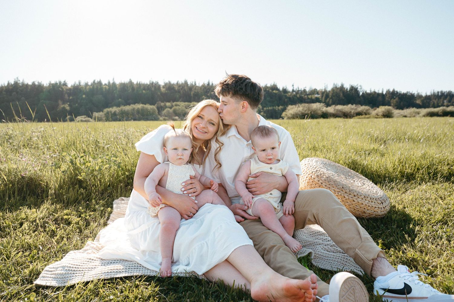 A family relaxes together on a blanket in a sunny meadow.