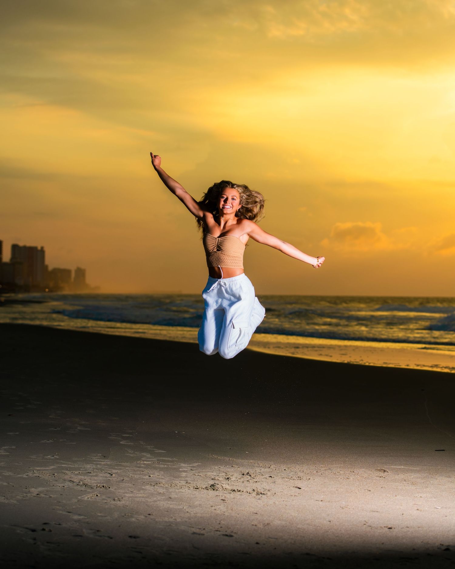Energetic beach jump silhouette against vibrant sunset sky. Myrtle beach photographer